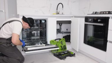 An electrician installs and connects the dishwasher to the electrical network.