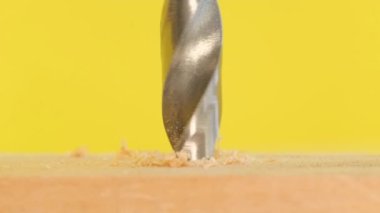 A close-up of an electric drill drills a wooden board. Macro video