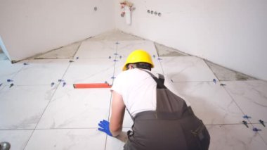 Laying ceramic tiles on the floor. The master measures the level of the floor.