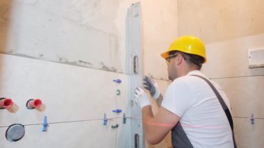 The builder measures the vertical deviation of the wall during the installation of ceramic tiles. Bubble level ruler, measuring and leveling concept