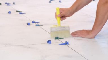 Construction repair of laying ceramic tiles on a concrete floor. A repairman worker cleans the floor with a brush