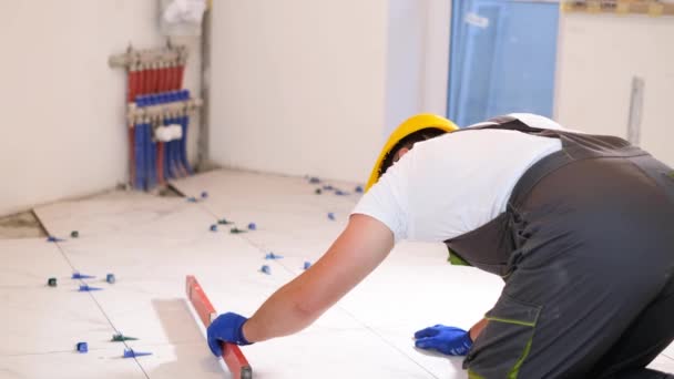 Builder Measures Level Floor Worker Laying Ceramic Tiles — Vídeo de Stock