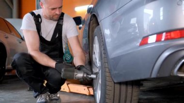The auto repairer installs or dismantles wheels in the workshop. Car repair and maintenance. Changing car tires from summer to winter