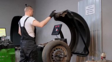 A car mechanic balances wheels on a special setup. Repair of automobile tires and rims.