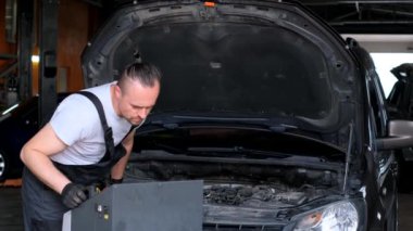 A worker with a pressure gauge for filling gas in the air conditioner compressor of a car. Car air conditioning inspection service. Car service