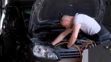 A car repairman checks the air conditioner in a car.