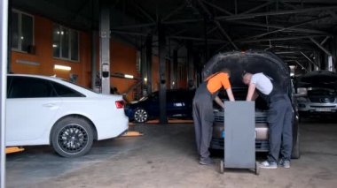 Two auto mechanics are checking the refrigerant level in the cars air conditioning system. Repair of car air conditioners.