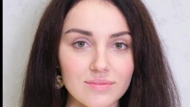 Portrait of a beautiful smiling brunette woman on a light background looking at the camera. Concept of natural beauty.