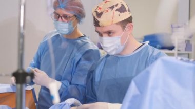 Tired, attentive, focused young surgeon during operation in operating room. Surgical intervention in patients with severe diseases. Sterilization during surgery