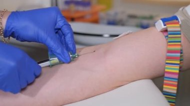 Close-up of a nurse taking blood from a vein in a patients arm for analysis. Diagnostics of the patients blood to establish a diagnosis.