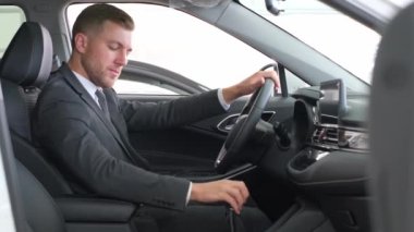 A businessman examines the interior of a new car. Buying a new electric car at a dealership. Car business concept