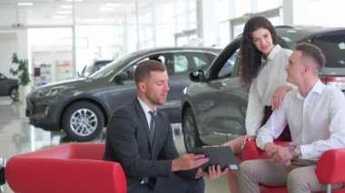 A lovely couple is talking to a manager while buying a car at a car dealership. Car dealership.