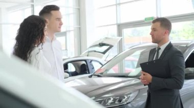 A car sales manager shows a new electric car in a car showroom. Car sales concept.