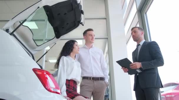 Male Car Sales Manager Shows New Electric Car Car Showroom — Wideo stockowe