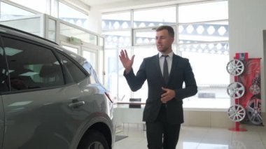 A man-manager of a car salon talks about new cars. Sale of cars in the dealership.