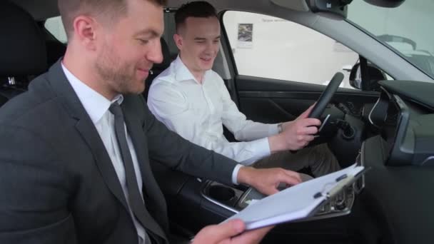 Young Man Talking Car Salesman Guy Client Buys Vehicle Showroom — стоковое видео