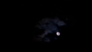 Time lapse of a bright yellow moon at night among dark clouds. Astrology concept.