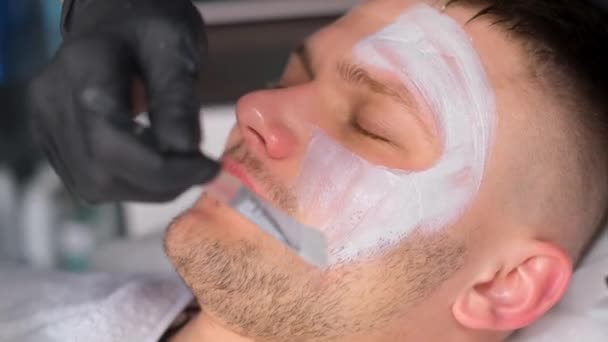 在一个放松的男人脸上贴上面具的特写 一个和美容师约会的男人男子痤疮的治疗 — 图库视频影像