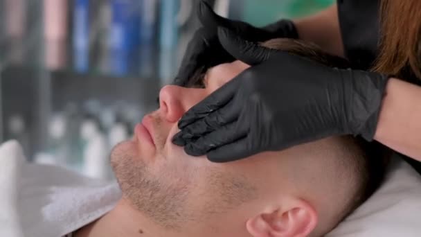 男性の顔マッサージ 手袋の美容師は若いリラックスした男に顔のマッサージを与えます — ストック動画