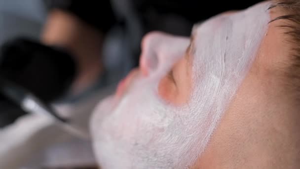 男の顔に医療マスクをつけながら男の顔のクローズアップ 皮膚科医は ブラシで修復マスクを適用します — ストック動画