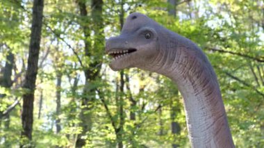 En büyük dinozorlar. Yavrularıyla birlikte bir anne dinozor ormanın ortasında duruyor. Uzun boyunlu bir dinozor. Otçul dinozorlar. Paleontoloji.