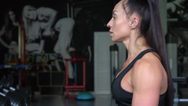 Brunette Works Out Gym She Lifts Dumbbells While Sitting Front — Vídeo de stock