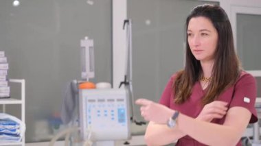 European female doctor in cherry medical gown looking away. A female doctor poses in a hospital office. Video 4k