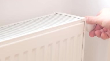 A close-up of a mans hand that turns on the heating in the house. Heating the house using a water radiator