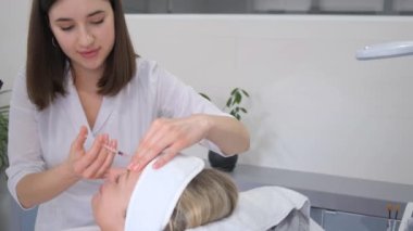 Botox injection to a beautiful woman at an appointment with a cosmetologist in an elite beauty salon. Fight against aging of the skin of the face.