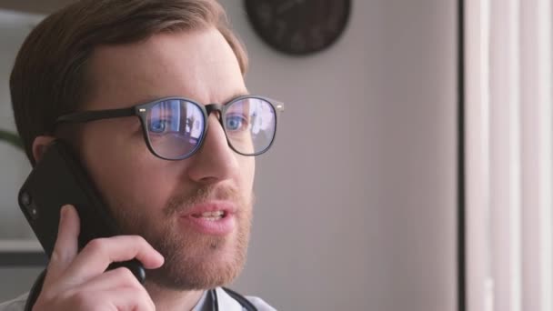 一个戴着眼镜在电话里聊天的有魅力的医生的特写 医生的工作日 专业青年实习生 — 图库视频影像