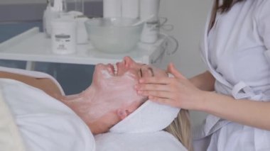 A cosmetologist massages a womans face, that lies on the shelf in an elite beauty salon. Proper facial care. Prevention of skin aging. Antiaging massage