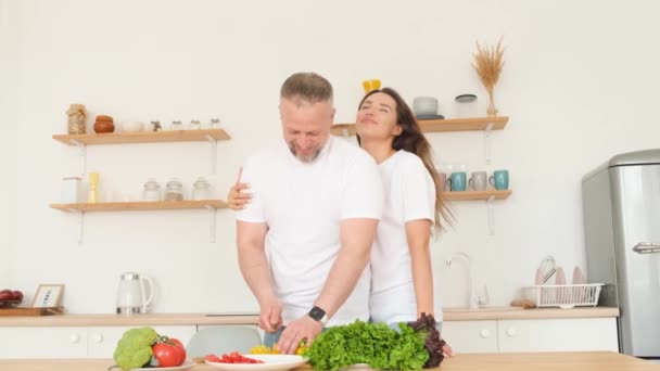 年轻可爱的男人和女人在家里做健康食品的时候笑了 快乐的夫妻喜欢在厨房里一起做饭 — 图库视频影像