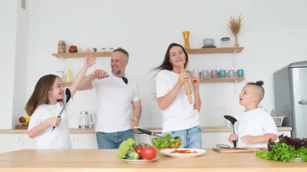 一家人边做饭边在厨房里跳舞和唱歌 儿子和女儿在和父母玩得很开心 — 图库视频影像