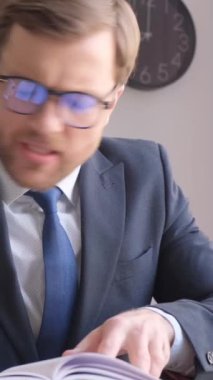 A tired office worker, he has a lot of work that he does not have time to do. Angry business worker. Vertical video