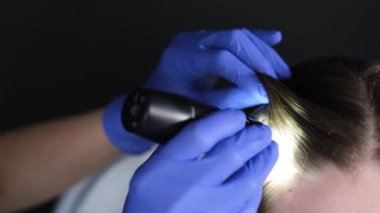  Bir kozmetik uzmanı-trikoloğu, trikop yardımıyla hastaların saçlarının durumunu teşhis eder..