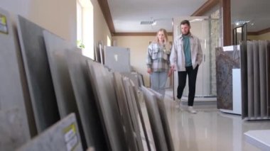 Güzel genç bir çift büyük bir hırdavatçıda ev yenilemesi için büyük seramik bir fayans seçiyor. Büyük bir modern seramik seramik seramik seçimi