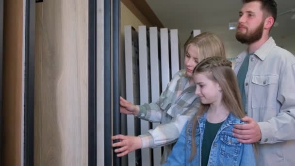 一对带着孩子的年轻夫妇在大量样品中挑选瓷砖 用你自己的手对房子进行现代的修理和设计 维修材料的家庭选择 — 图库视频影像