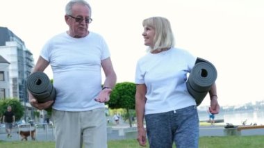 Spor yaptıktan ya da yoga yaptıktan sonra spor paspaslarıyla gülümseyen yaz çifti. Emeklilikte sağlık ve sağlıklı bir yaşam tarzı.