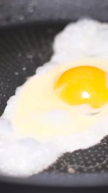 Kızartma tavasında yumurta, ayçiçeği yağında, yakın plan. Dikey video.