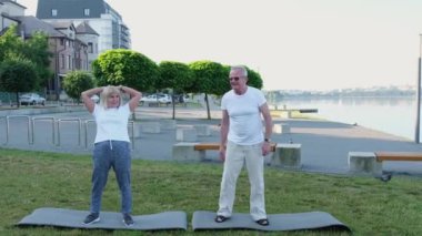 Yaşlı bir çift şehir parkında jimnastik yapıyor. Emeklilikte spor hayatı.