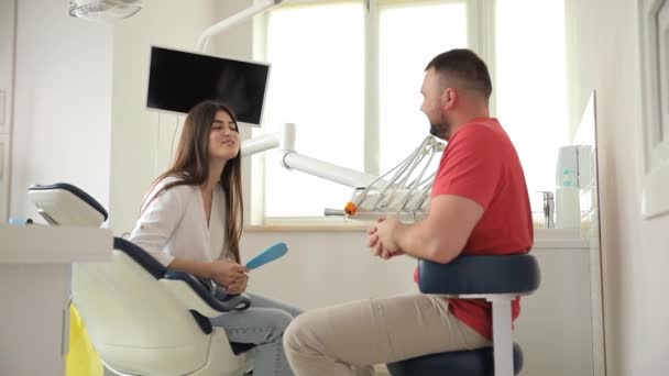 Ein Junger Zahnarzt Der Zahnarztpraxis Spricht Mit Einem Patienten Und — Stockvideo