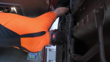 Araba bir araba atölyesinde araba tekerleklerini ayarlamak için ayakta duruyor. Dikey video.