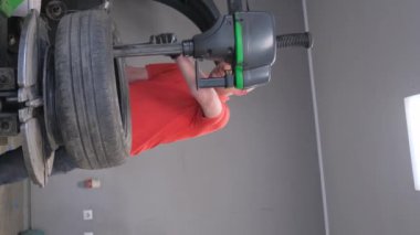 Bir tamirci bir araba lastiğini tamir eder. Lastik patladı. Araba servisi. Dikey video.