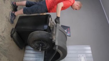 Bir araba tamircisi arabanın lastiklerini dengeler. Araba tamiri kavramı. Dikey video.