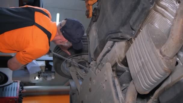 Professional Mechanic Repairs Wheels Car Lifted Lift Workshop Vertical Video — Stock Video