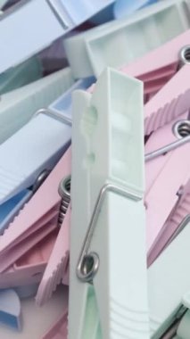 Çamaşırları kuruturken tutmak için çok renkli plastik mandallar. Renkli bir geçmiş. Daire şeklinde döndür. Dikey video