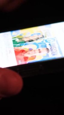 Geceleri cep telefonuna bakıp sosyal ağda gezinen bir adamın yakın çekimi. Cep telefonu uygulaması kullanırken parmaklarınızla cep telefonunuza dokunmak. Dikey video