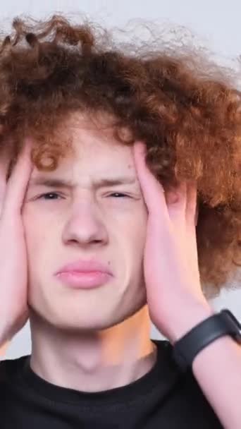 Nahaufnahme Eines Überraschten Rothaarigen Lockigen Jungen Auf Hellem Hintergrund Kopfschmerzen — Stockvideo