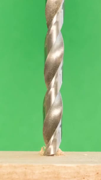 在绿色背景上旋转的木工钻头的特写 一个闪亮的金属钻头在工作 打孔的施工工具 慢动作垂直录像 — 图库视频影像