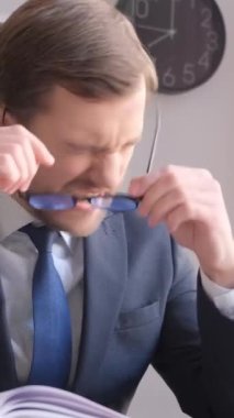 Çok yorgun, sinirli genç bir bilişim işçisi masanın başında oturuyor. Yorucu zihinsel işler..